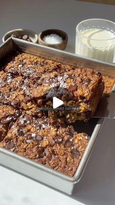 a pan filled with granola bars next to a cup of milk and spoons