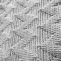 a knitted blanket is shown in grey and white colors, as well as the pattern