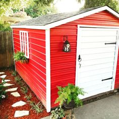 a red and white shed sitting next to a tree