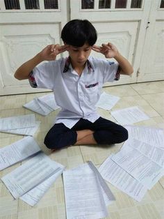 a young boy sitting on the floor surrounded by papers that have been placed in front of him