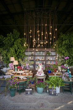 a room filled with lots of potted plants and lights hanging from the ceiling above