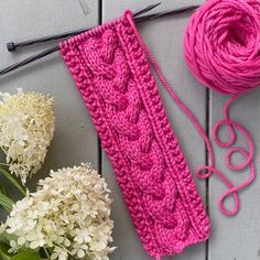 a pink knitted headband next to white flowers