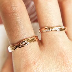 a woman's hand with two gold rings on her left and the other one has a diamond band