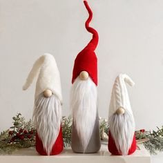 three christmas gnomes sitting on top of a shelf