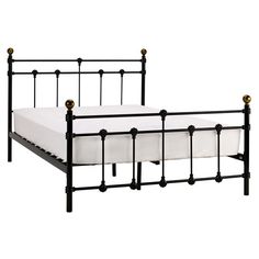 a black metal bed frame with white sheets and gold knobs on the headboard