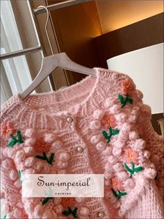 a pink knitted sweater with flowers on it