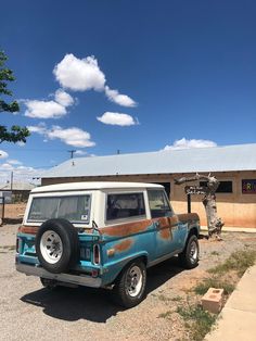 a blue and white jeep parked in front of a building