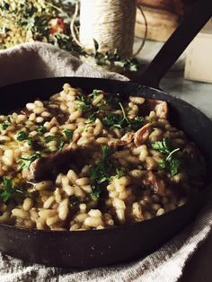 a skillet filled with rice and meat on top of a table next to a napkin