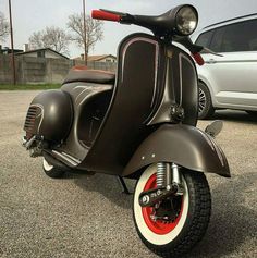 an old scooter is parked in a parking lot