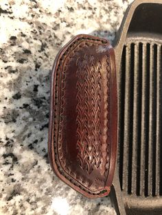 a close up of a brown leather case on a counter top with a black grill grater