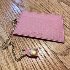 a pink card case with a keychain attached to it on a wooden table