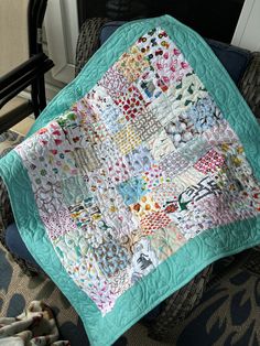 a quilted blanket sitting on top of a chair next to a stuffed animal toy