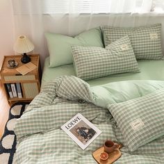 a bed covered in green and white checkered comforter next to a night stand