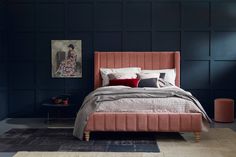 a bedroom with black walls and a pink bed in the middle is decorated with red pillows