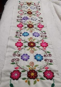 an embroidered table runner with flowers on it