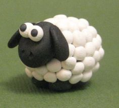 a black and white sheep made out of marshmallows on a green surface