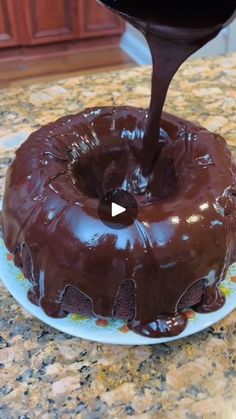 a chocolate bundt cake being drizzled with icing on a plate