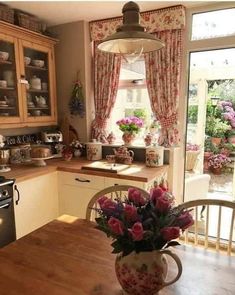 a vase with flowers sitting on top of a wooden table next to a stove and oven