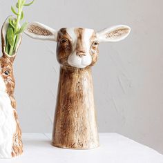 two small ceramic animals with flowers in their mouths, one is brown and the other is white