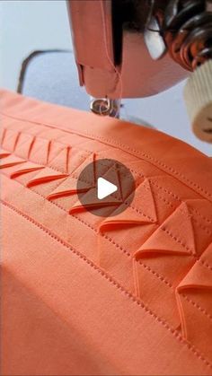 an orange piece of fabric being sewn with a sewing machine