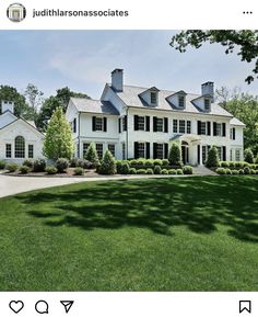 a large white house sitting on top of a lush green field in front of trees