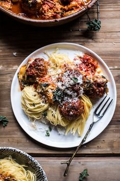 two plates of spaghetti and meatballs on a wooden table