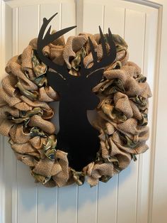 a deer head on a burlock wreath hangs on the front door to welcome guests