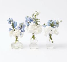 three clear vases with blue and white flowers in them