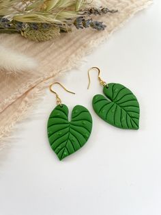 green leaf shaped earrings sitting on top of a table