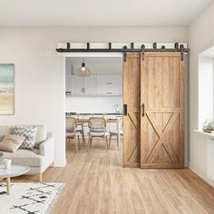 a living room filled with furniture next to a wooden floor and sliding doors that lead into a kitchen