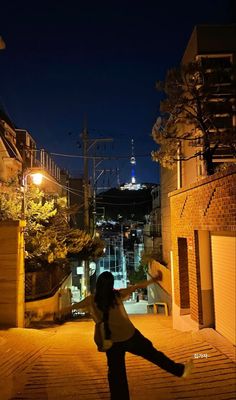 a person standing in the middle of an alleyway at night with their arms spread out