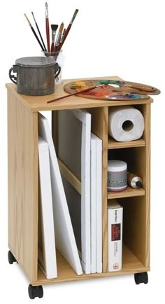 a wooden shelf with various items on it and some paintbrushes in the background