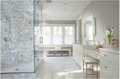 a large bathroom with marble floors and white walls, along with a walk in shower