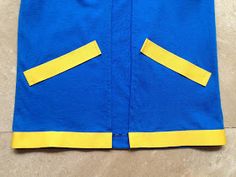 a blue jacket with yellow trims on the front and back, sitting on a floor