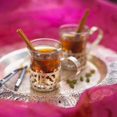 two mugs filled with tea sit on a doily