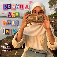 a woman taking a selfie in front of the ocean with colorful letters behind her