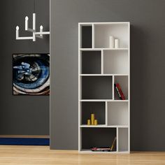 a white book shelf sitting on top of a hard wood floor next to a gray wall