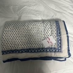 a white and blue pillow on top of a bed with a tag attached to it