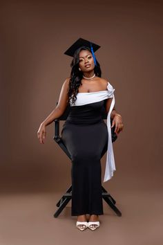 a woman sitting in a chair wearing a graduation cap and gown with her hands on her hips