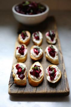 small cranberry and cream filled bagels on a wooden board with leaves in the middle