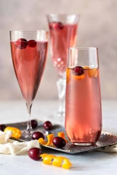 two glasses filled with cranberry wine and garnished with orange peels