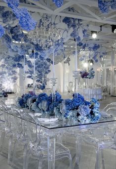 a glass table with blue flowers on it and chandeliers hanging from the ceiling