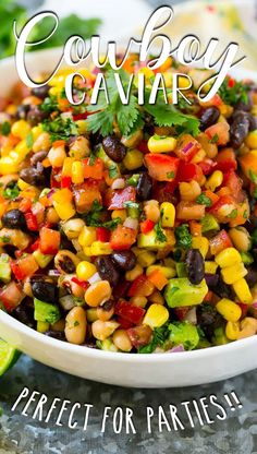 a white bowl filled with corn and black beans next to lime wedged cilantro