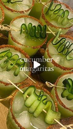 some green drinks are sitting on sticks with the words cucumber margaritas in them