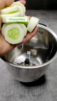 a person is holding sliced cucumbers in a metal bowl