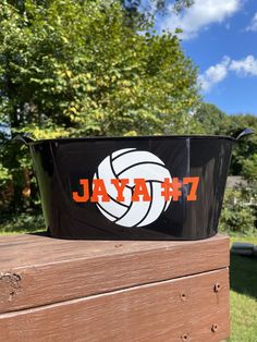 a black basket with an orange and white logo on it sitting on top of a wooden table