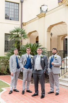 a group of men in suits standing next to each other on a brick floored walkway