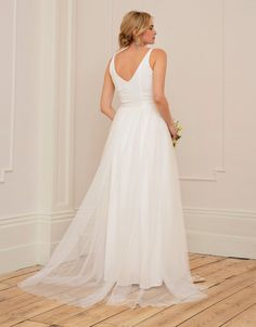 a woman in a white wedding dress standing on a wooden floor with her back to the camera