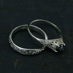 two silver wedding rings sitting on top of a black surface