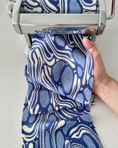 a person is holding a roll of blue and white fabric on a rolling machine with their hand